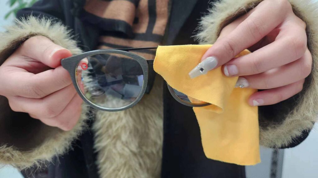 Woman wiping glasses with an yellow eyeglass cloth