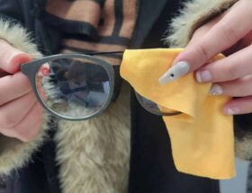 Woman wiping glasses with an yellow eyeglass cloth
